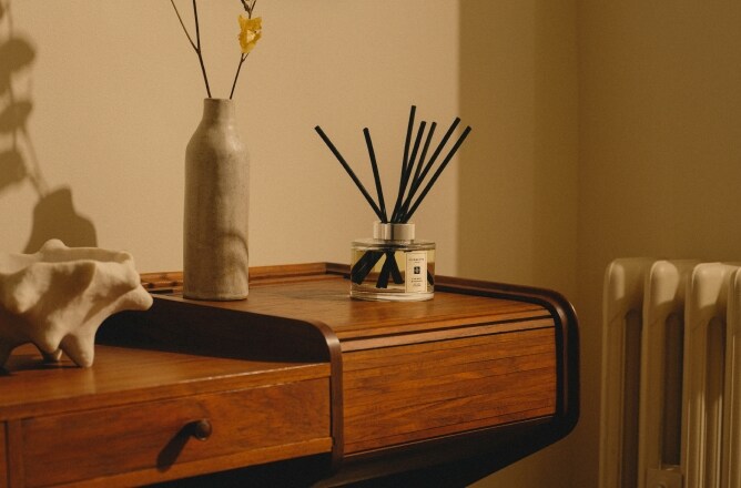 Jo Malone London Diffuseur sur une table en bois avec un vase et des fleurs